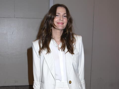 Drew Barrymore mit offenen Haaren und einem weißen, gestreiften Anzug.