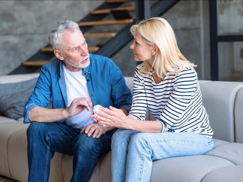 Mann und Frau sitzen auf einer hellen Coach und führen ein Gespräch.