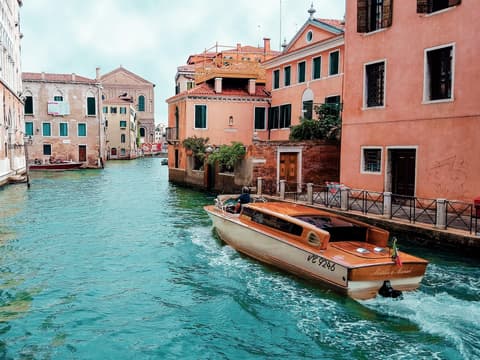 Es gibt viele Orte in Europa, die man gesehen haben muss. Ein Kanal in Venedig mit bunten Häusern und einem Boot.