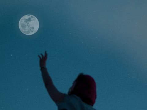 Frau streckt Arm zum Mond