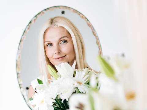 Blonde Frau schaut in den Spiegel