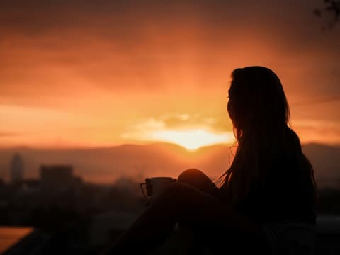 Frau schaut in den Sonnenaufgang