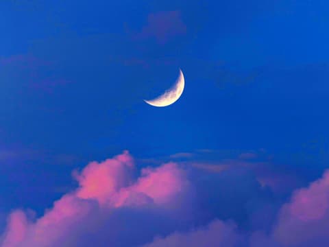 Sichelmond vor blauem Himmel und rosa Wolken