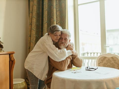 Eine Frau umarmt von hinten einen Mann und kuschelt sich an ihn.
