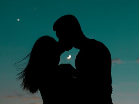 4 Sternzeichen steht durch den Oktober-Neumond eine große Wende im Liebesleben bevor. Pärchen küsst sich vor Mondhimmel