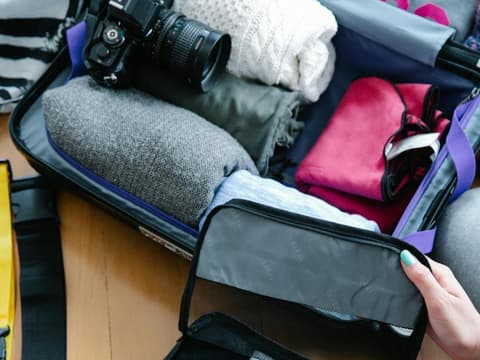 Voller Koffer mit Kleidung, Kamera und Sortierfächern.