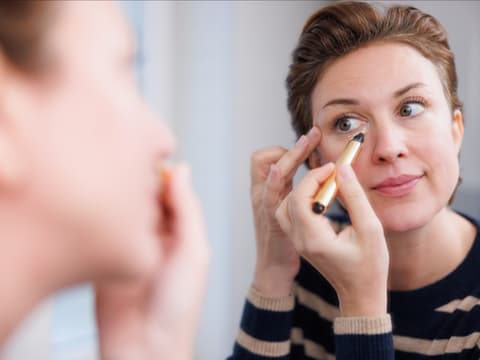 Frau trägt Concealer auf Frau trägt Concealer auf