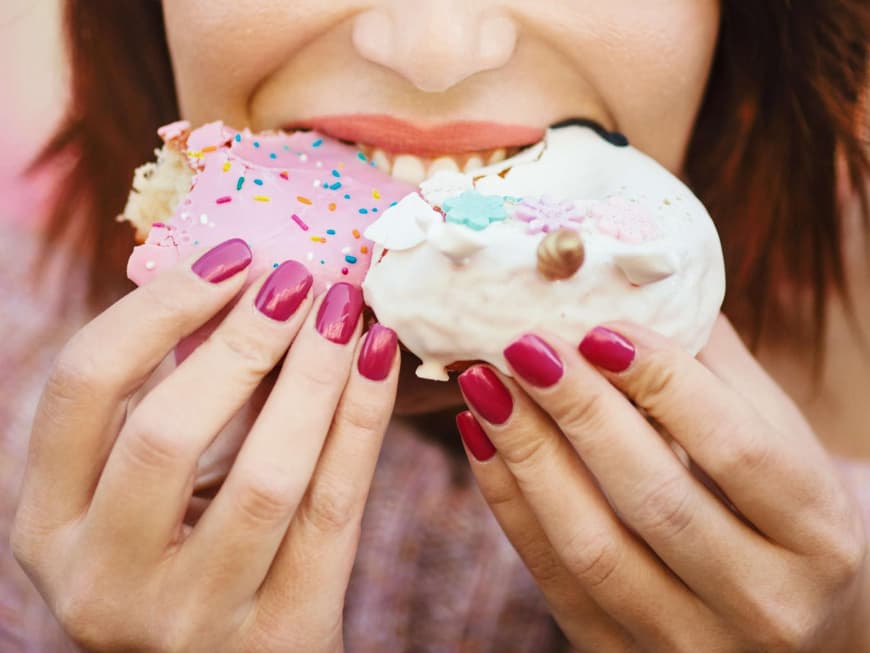 Frau mit lackierten Fingernägeln isst Kuchen
