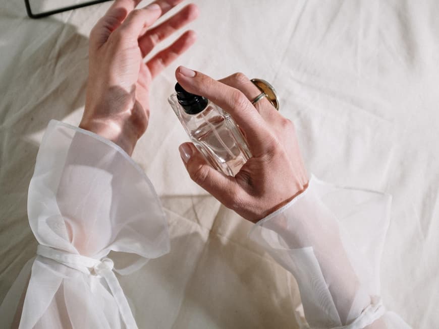 Frau sprüht sich Parfum aus