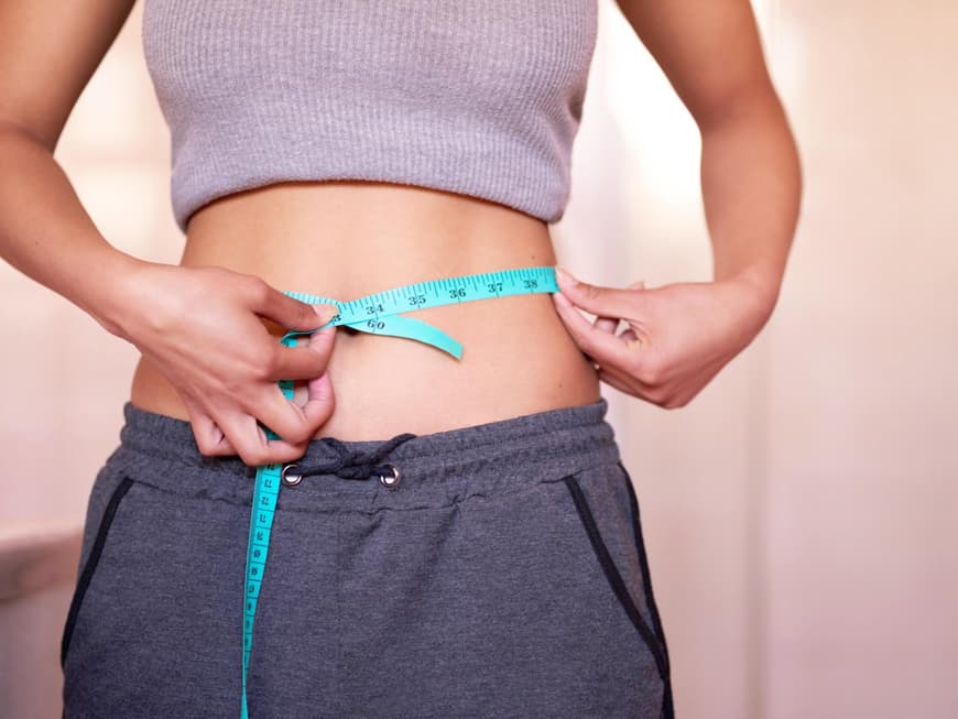 Frau mit Maßband am Bauch
