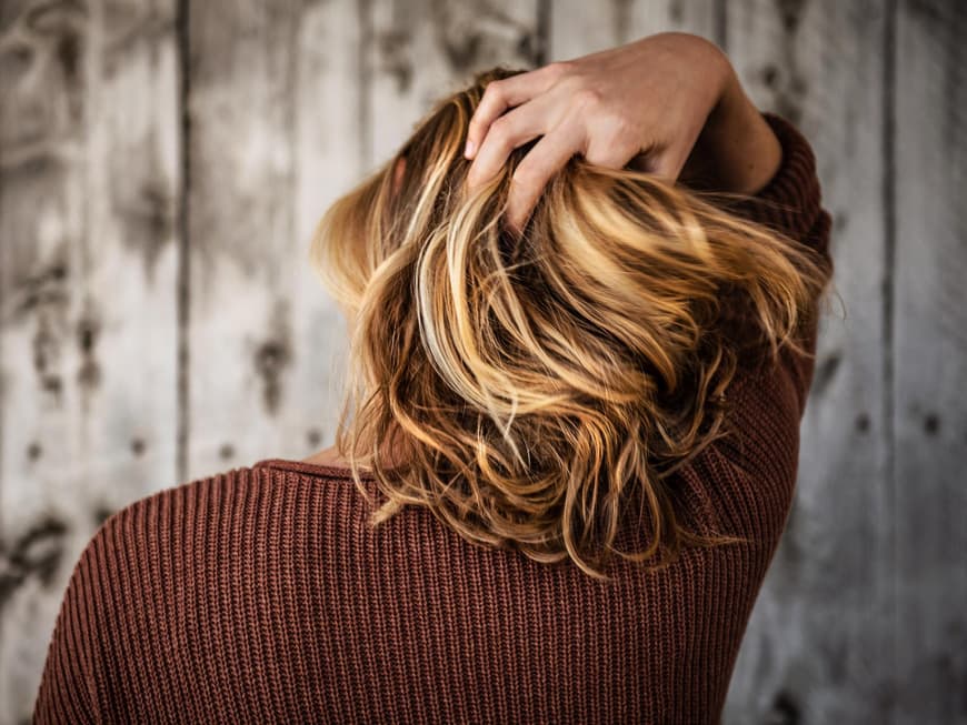 Frau fasst sich in die Haare