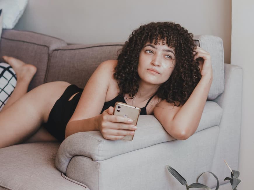 Frau mit Handy auf Sofa 