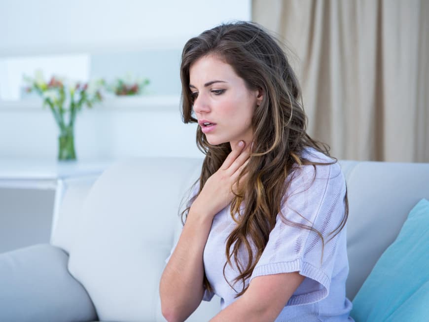 Frau fasst sich an den Hals