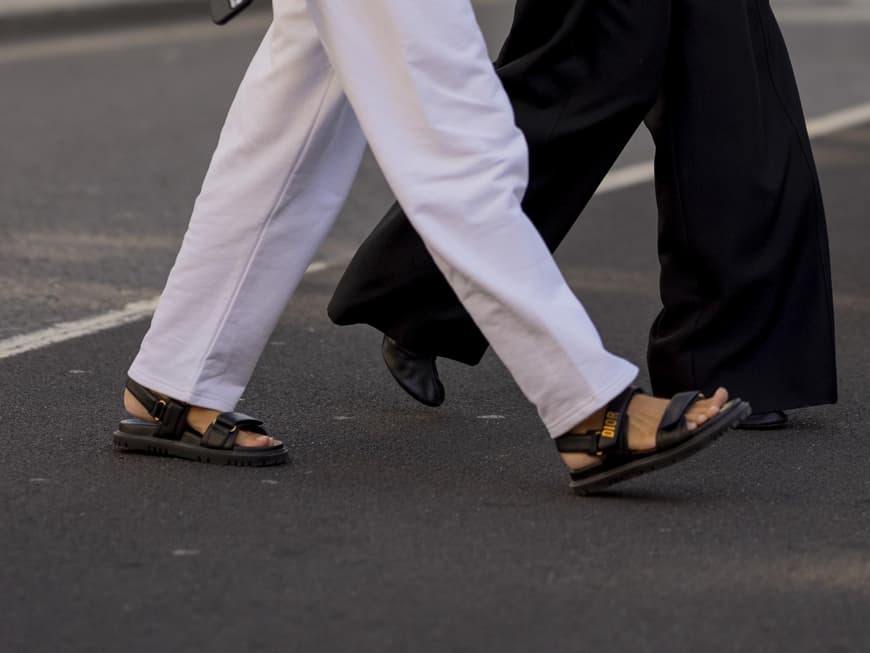 Frau mit weißen Hosenanzug und flachen Sandalen