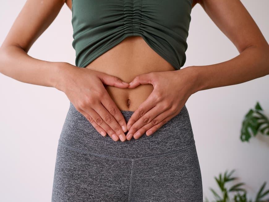 Frau mit Händen in Herzform auf Bauch