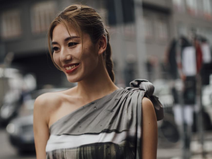 Mailand Fashion Week Frau trägt Kleid und Zopf lächelt