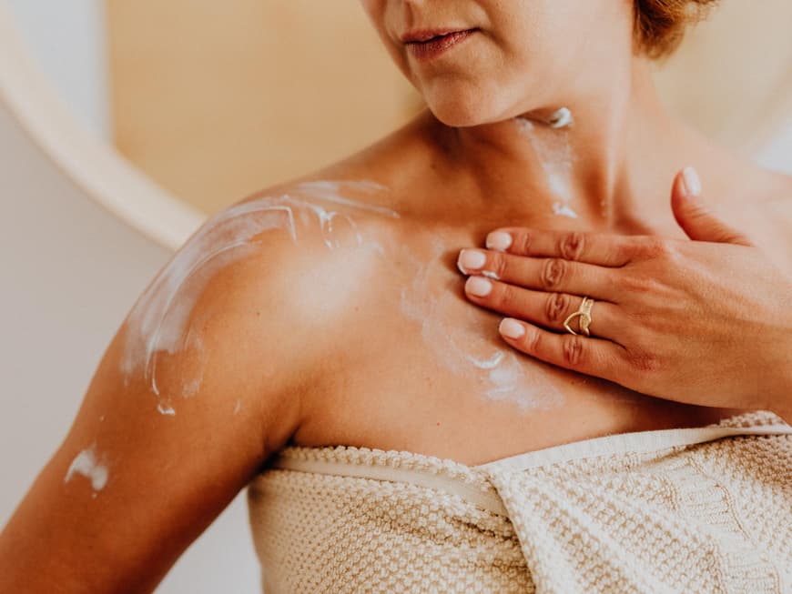 Welche Bodylotion für trockene Haut die Beste ist, verrät Stiftung Warentest. Frau trägt Bodylotion auf