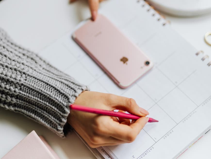 Frau schreibt mit einem Stift etwas in ihren Kalender