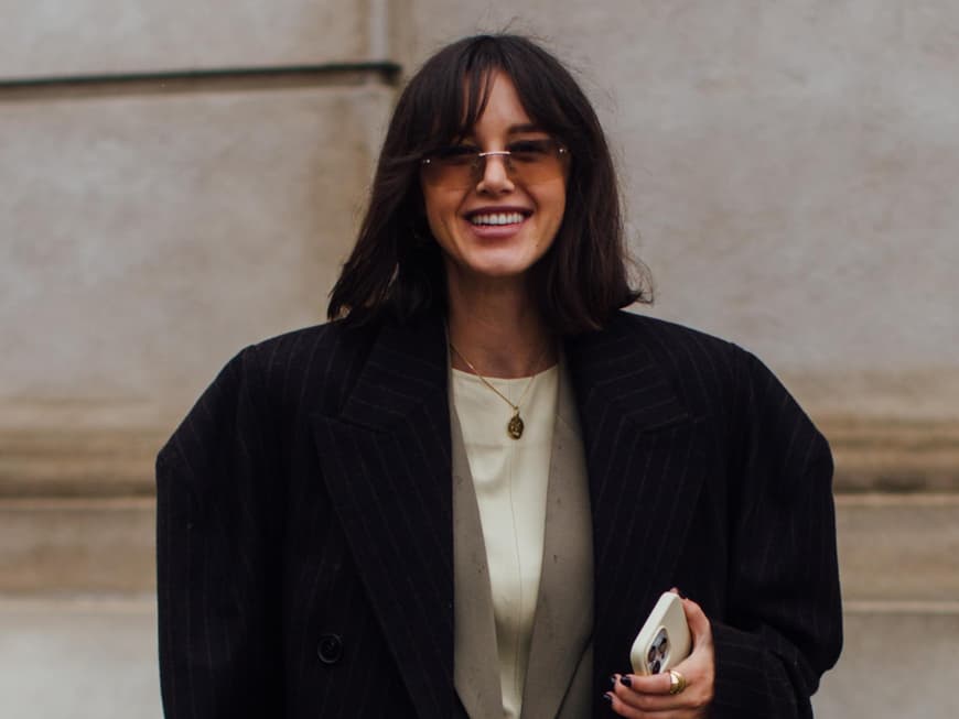 Frau auf Copenhagen Fashion Week trägt Haare mit Pony und Fashion Look mit Blazer