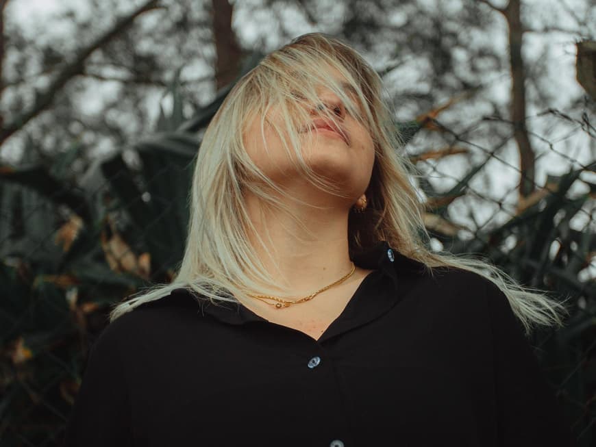 Blonde Frau mit Haaren vor dem Gesicht