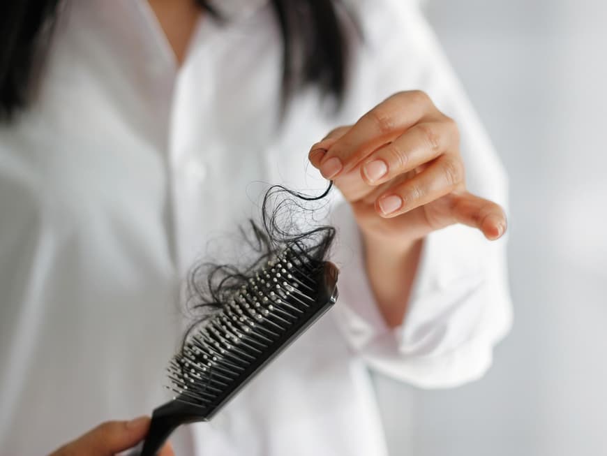 Frau hält Bürste mit Haaren in der Hand Frau hält Bürste mit Haaren in der Hand