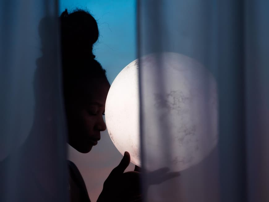 Frau mit Dutt hält eine Kugel in der Hand, die aussieht wie der Mond