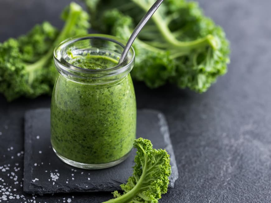 Grünkohl-Pesto im Glas auf einem grauen Tisch