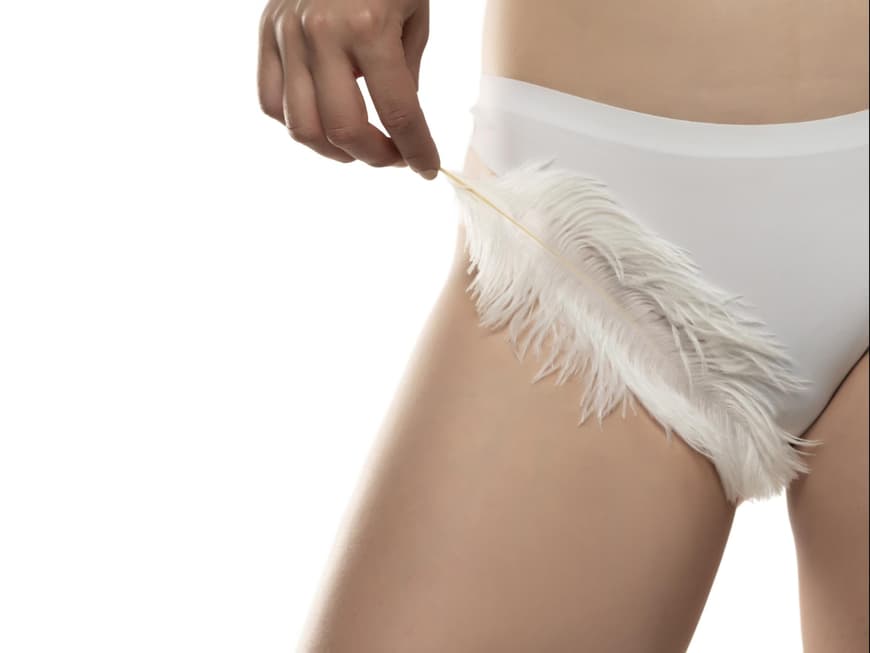 Frau in Unterhose hält Feder in der Hand