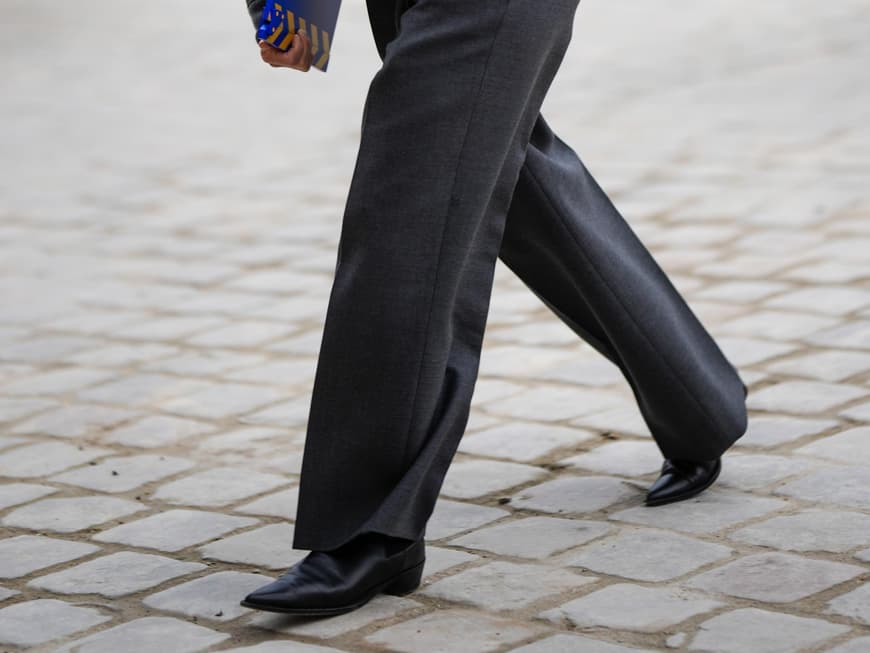 Stylische Frau trägt auf Paris Fashion Week Ankle Boot und graue weite Hose plus Jacke Stylische Frau trägt auf Paris Fashion Week Ankle Boot und graue weite Hose plus Jacke