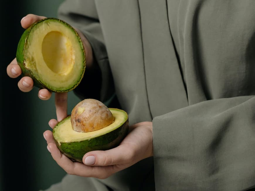 Frau hält eine Avocado in der Hand