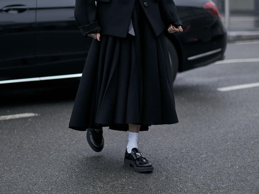 Frau trägt auf Mailand Fashion Week schwarze Prada Loafer Frau trägt auf Mailand Fashion Week schwarze Prada Loafer