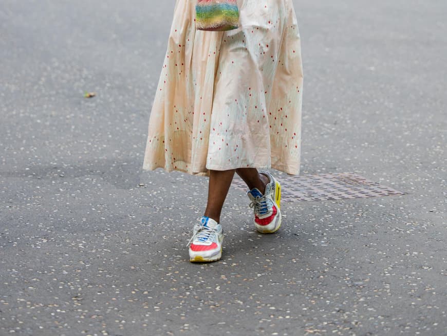 Frau trägt bunte Sneaker und ein Midikleid auf London Fashion Week