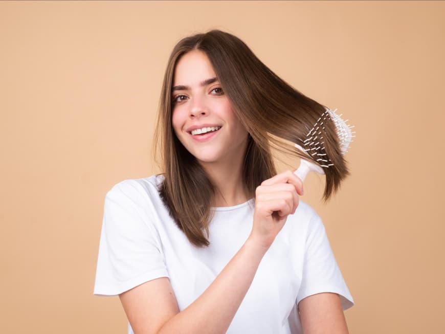 Schädliche Haarprodukt-Inhaltsstoffe Frau kämmt sich die Haare