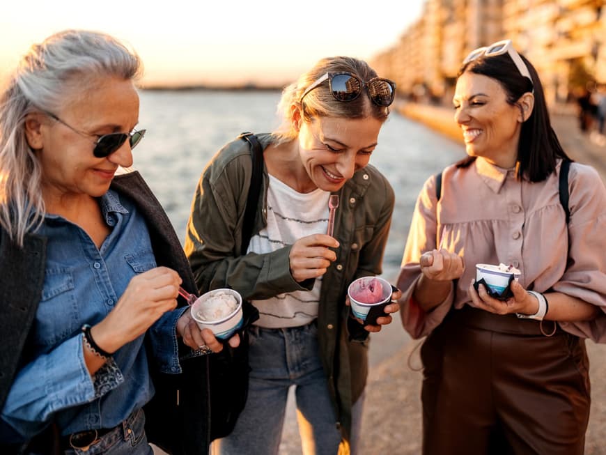 Drei Frauen lachen essen ein Eis im Becher