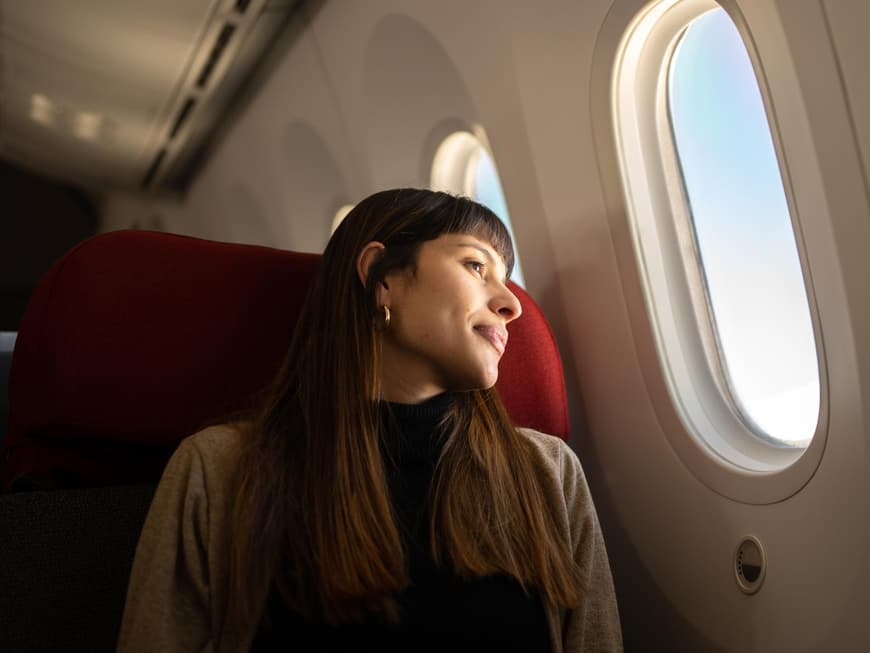 Frau sitzt im Flugzeug und guckt aus dem Fenster