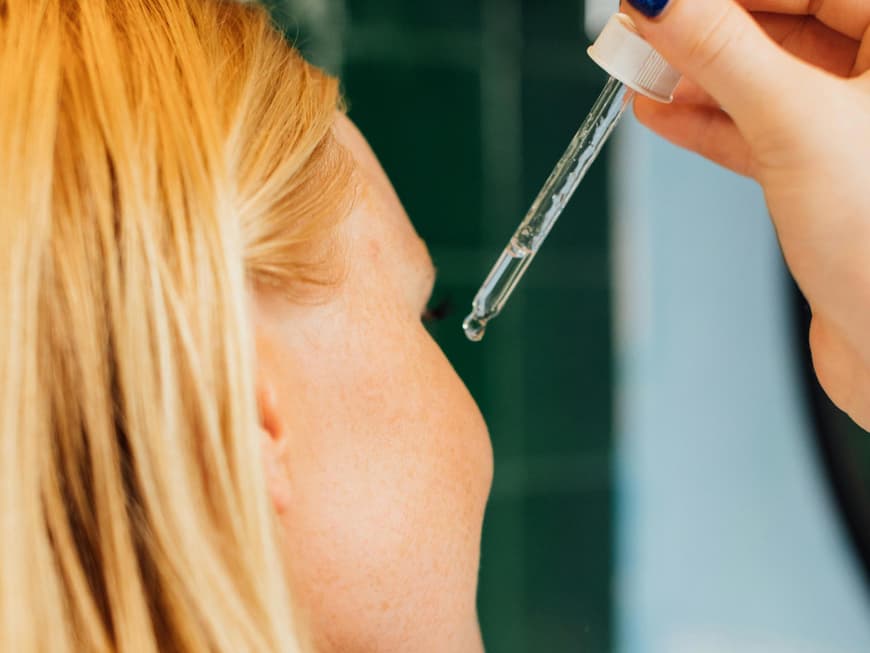 Frau trägt Serum auf ihr Gesicht auf