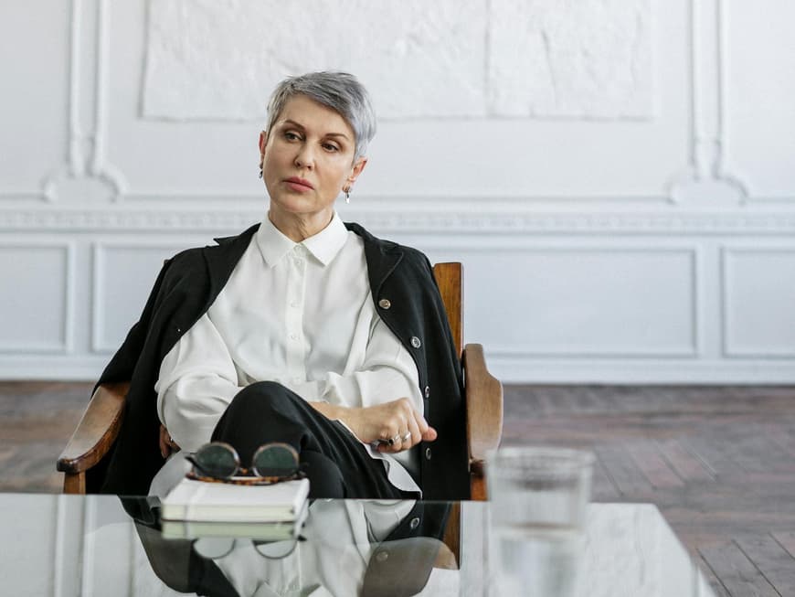 Frau sitzt im Sessel vor einem Couchtisch.
