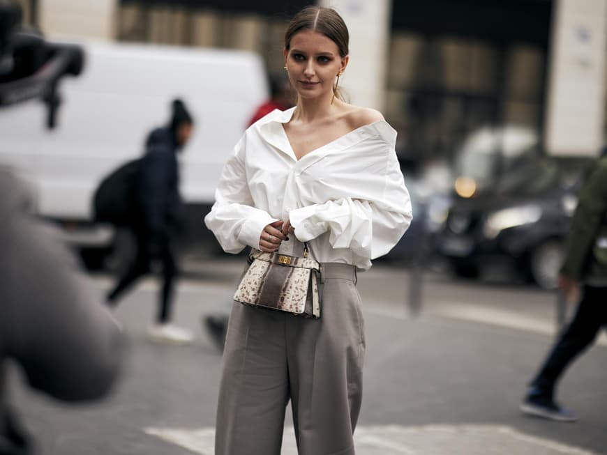 Frau trägt auf Paris Fashion Week weiße Bluse und graue Hose Streetstyle plus Tasche