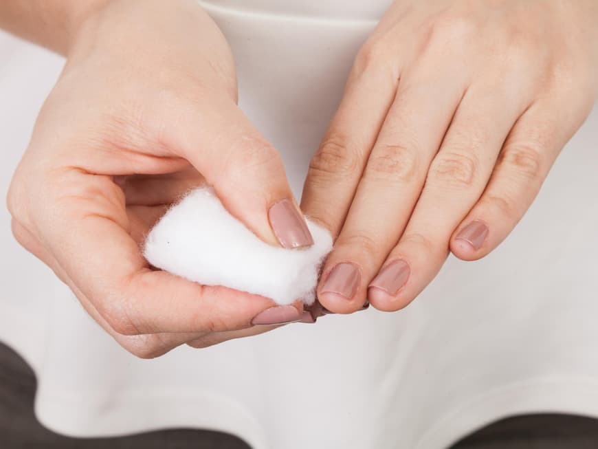 Nagellack von den Fingernägeln mit einem Wattepad entfernen