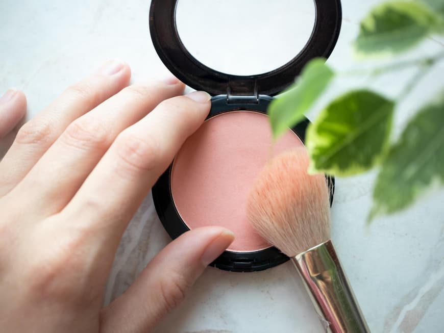 Blush in Puderform mit einem Pinsel.