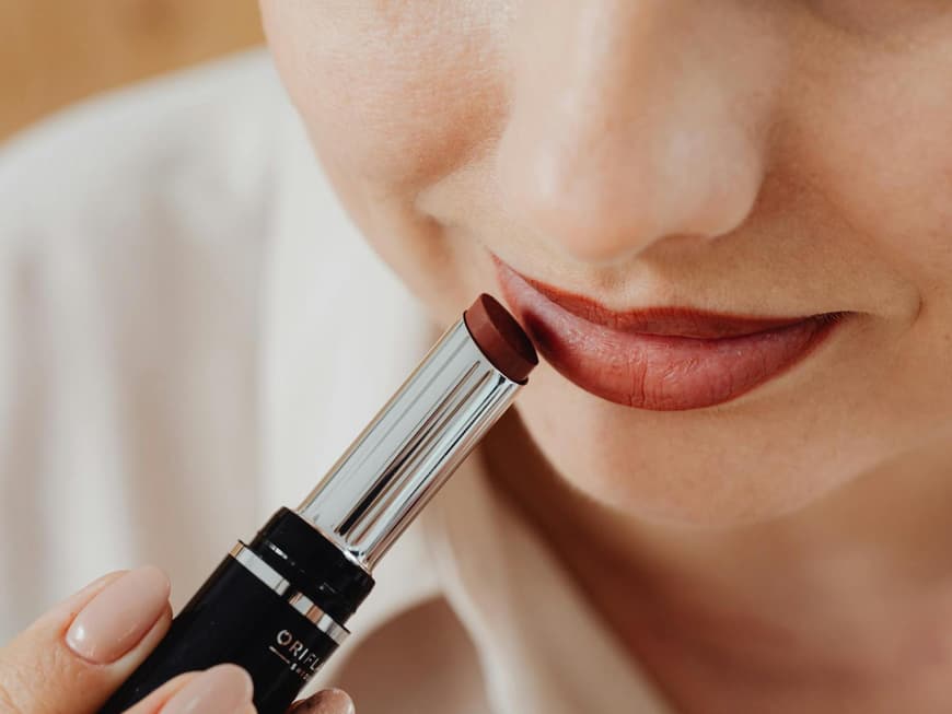 Frau schminkt sich mit Lippenstift.