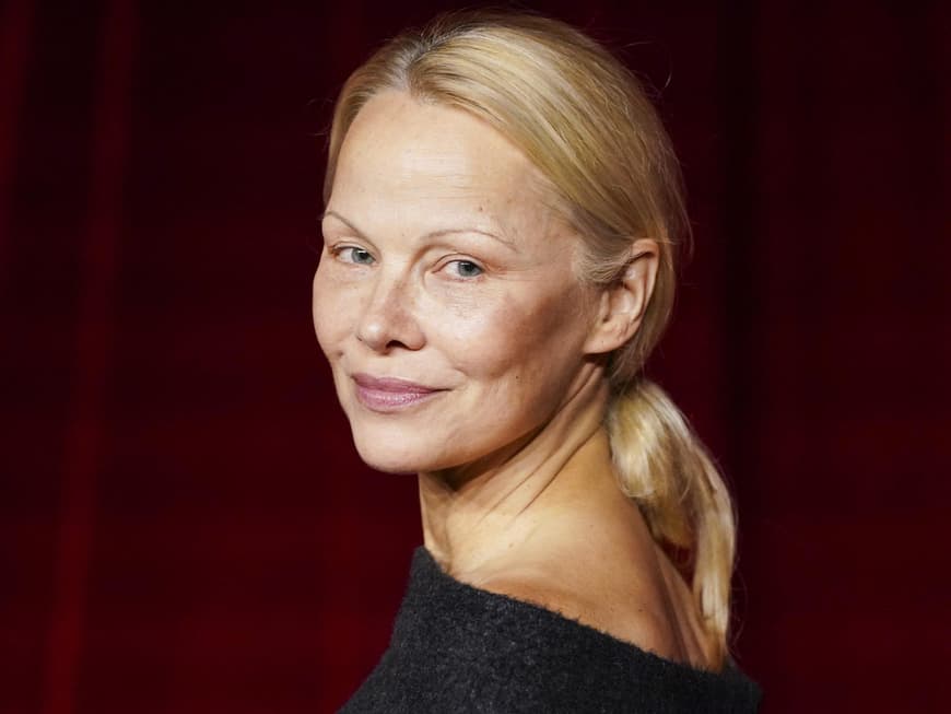 Skinny Brows sind wieder im Trend, wie Pamela Anderson beweist. Pamela Anderson guckt über die Schulter nach hinten.