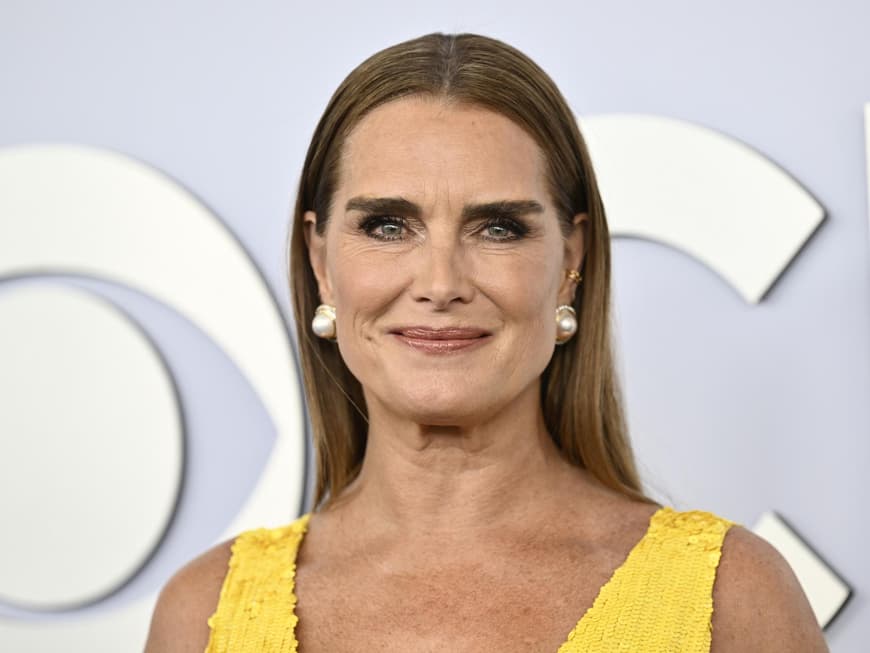Brooke Shields mit Perlen Ohrringen und einem gelben Kleid.