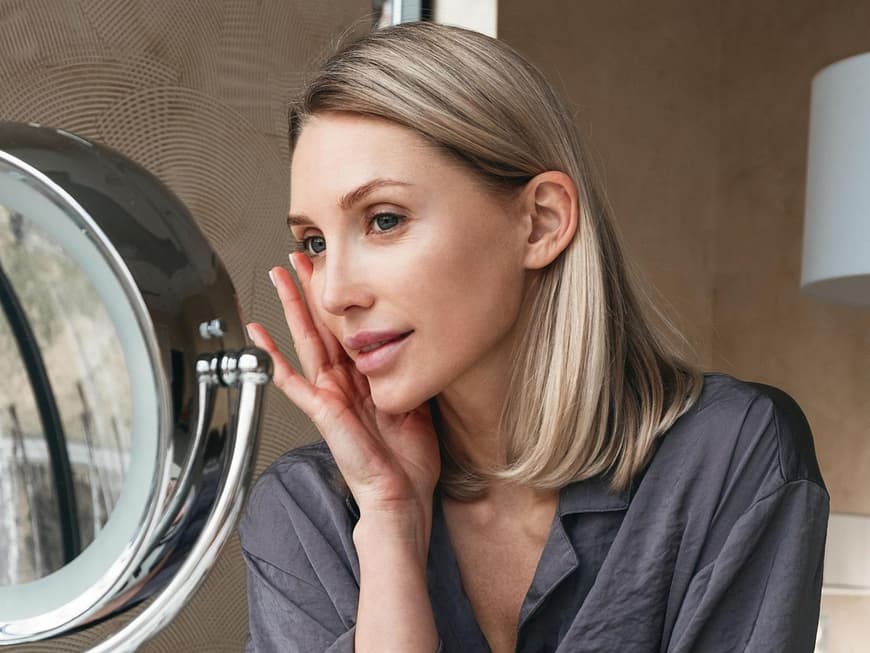Frau trägt Make-up auf ihr Gesicht auf.
