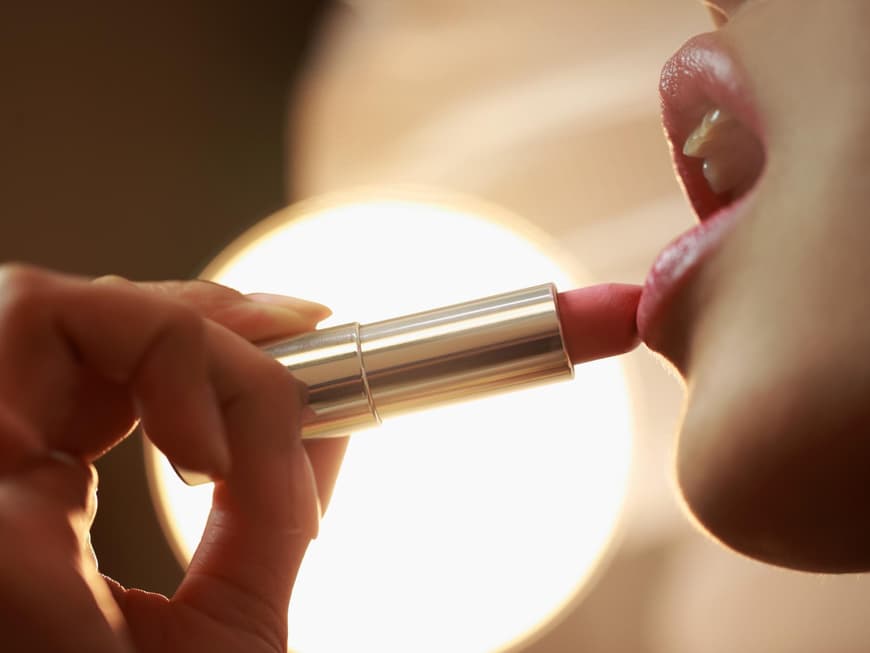 Ein Glossy Balm spendet Feuchtigkeit und Farbe. Frau trägt Lippenstift auf die Lippen auf.