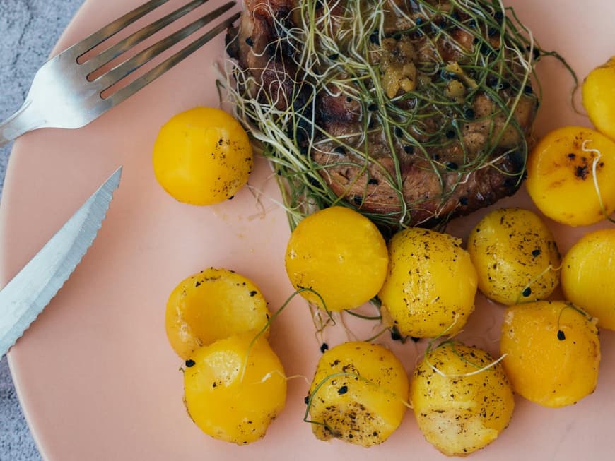 Kartoffeln und Fleisch auf einem rosanen Teller.
