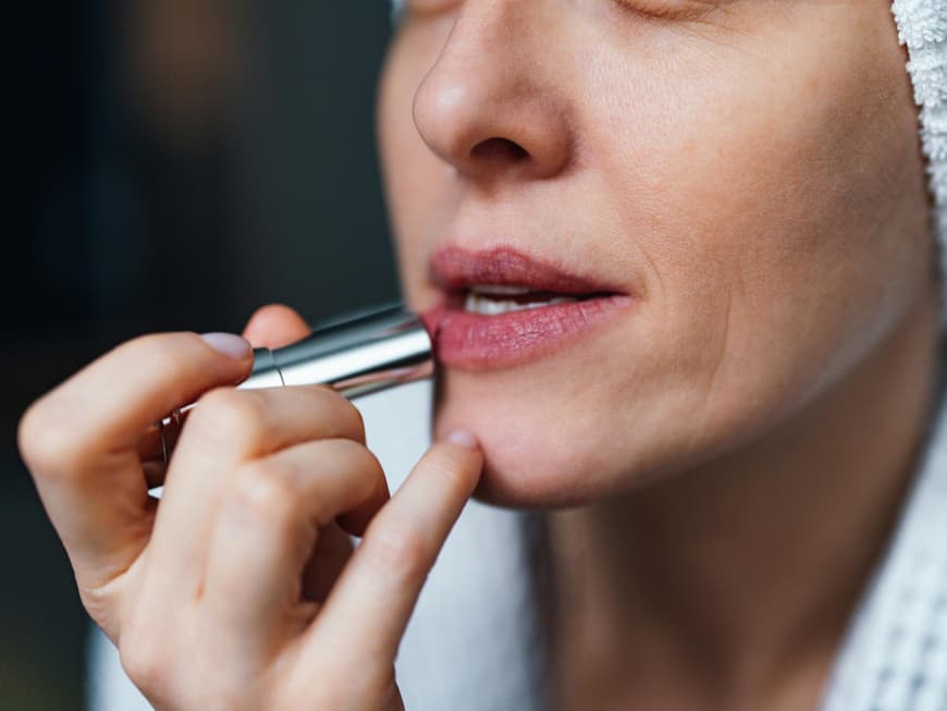 Matter Lippenstift ist wieder angesagt. Frau trägt Lippenstift auf ihre Lippen auf.