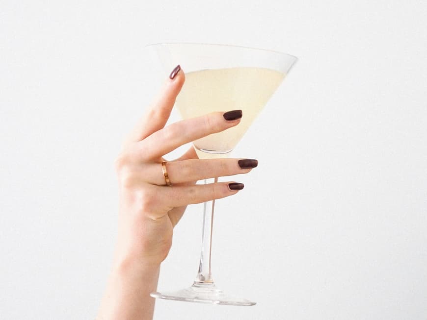 Frauenhand mit Nagellack hält Sektglas