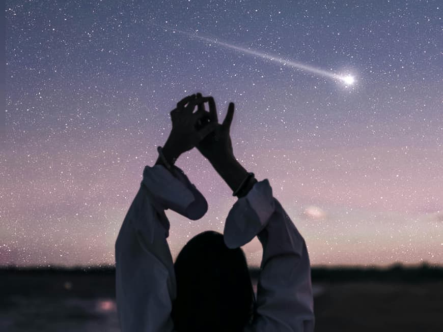 Frau steht vor Sternenhimmel