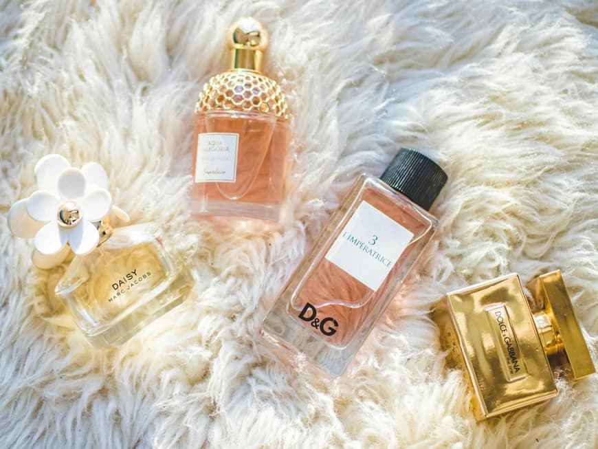 Verschiedene Parfums auf einem flauschigen weißen Teppich.